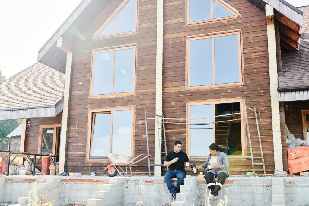 Two individuals enjoying coffee during a break at a wooden house construction site.